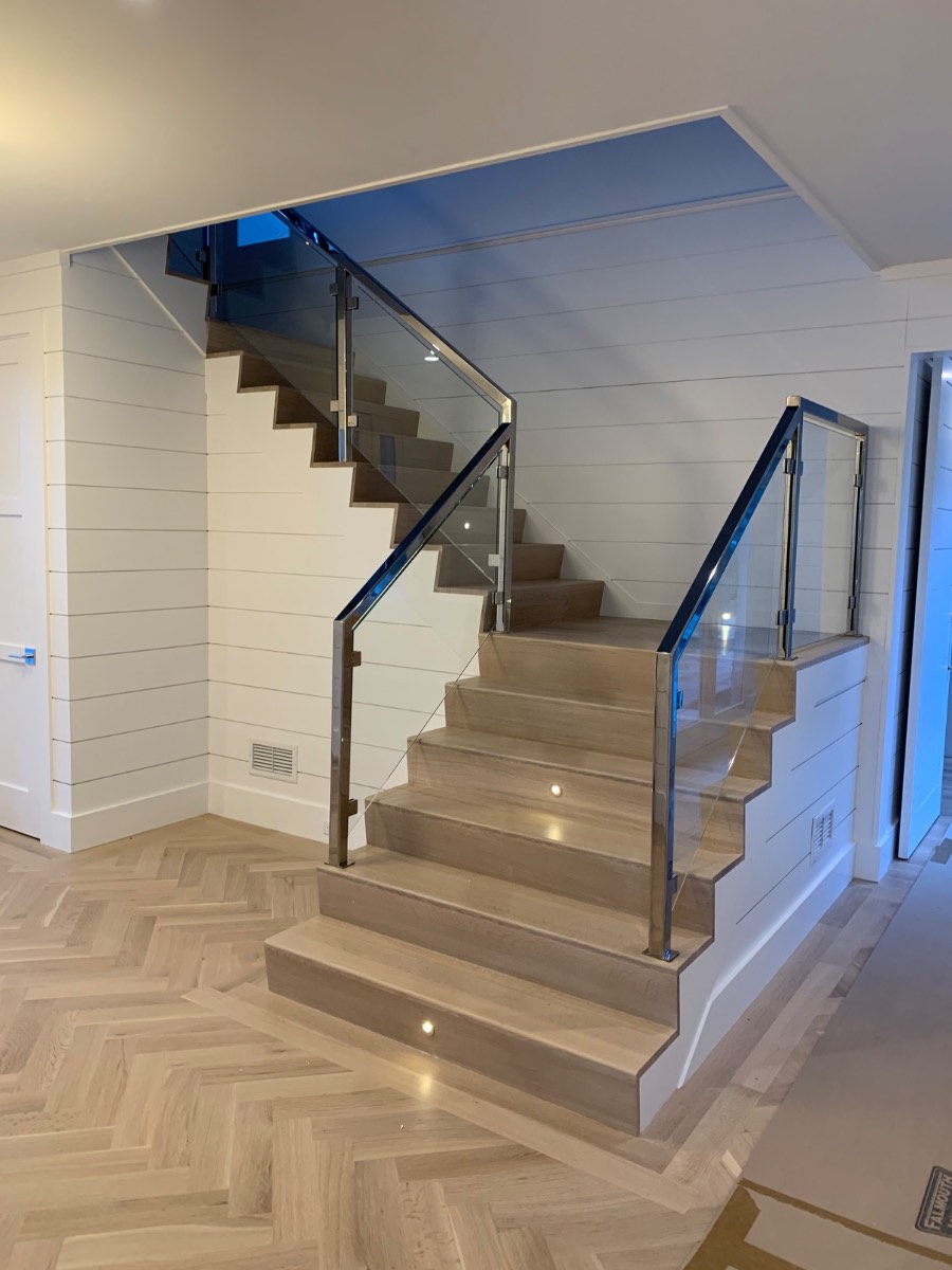 Custom staircase with glass railing and herringbone floor in Falmouth