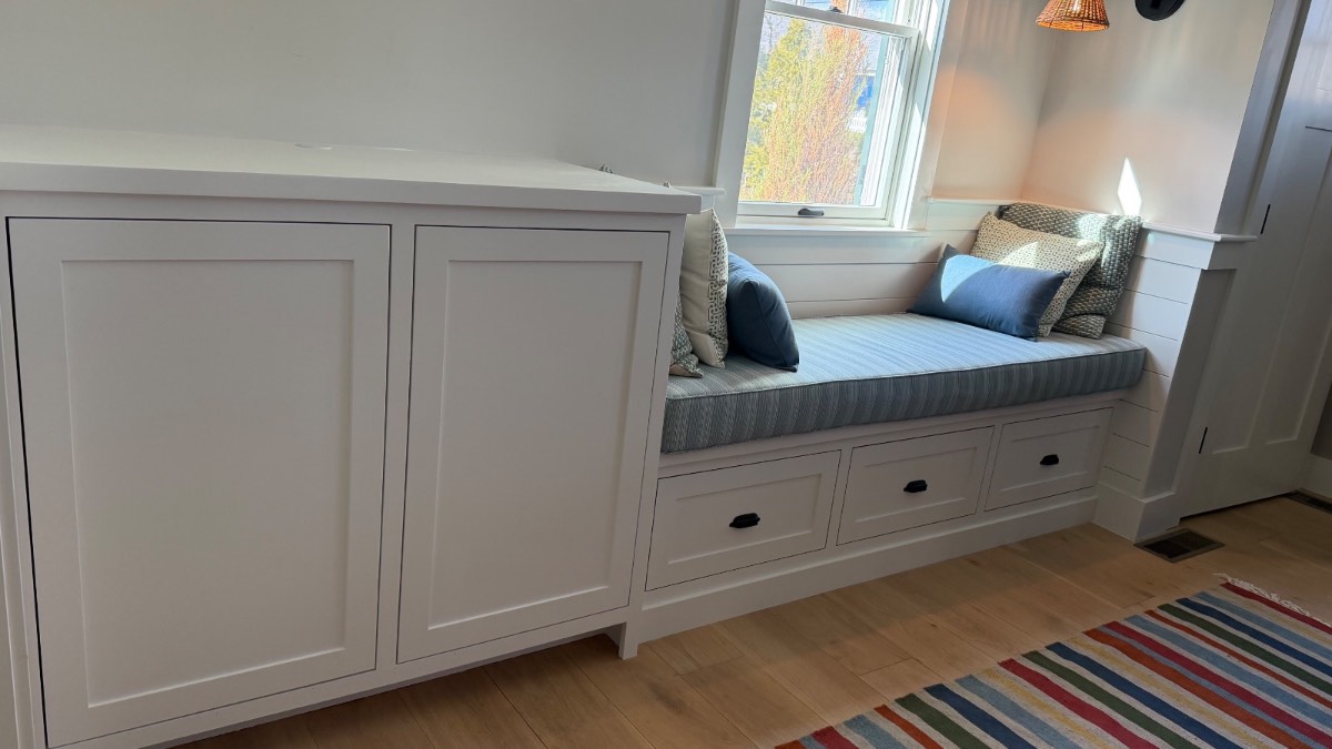 Custom white built-in window seat with storage in a coastal Cape Cod home