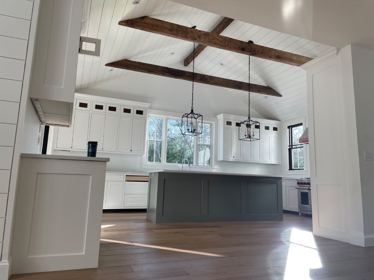 Custom white kitchen with reclaimed wood beams, gray island, and shiplap vaulted ceiling on Cape Cod