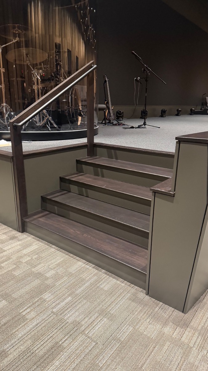 Custom stained-wood stage steps and handrail at Reach Church