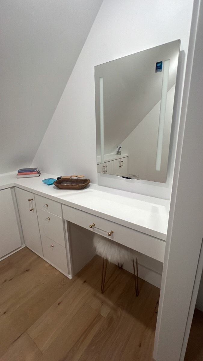 Custom white make-up vanity built into a dormer with lit mirror
